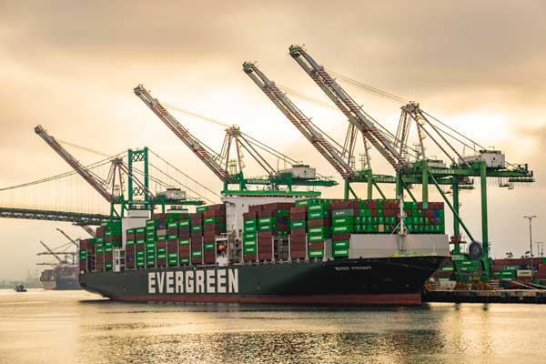Evergreen ship docked at the Port of Los Angeles during sunset.
