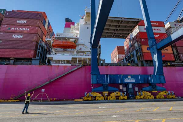 A dockworker ensures safe cargo-handling in front of a container ship docked at the Port of Los Angeles