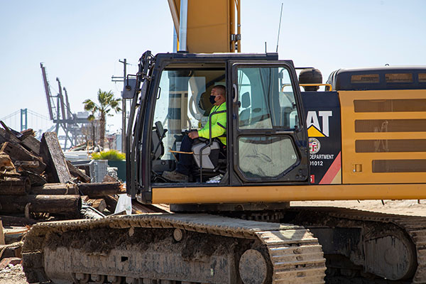 A construction worker drives tractor at the Port of Los Angeles.