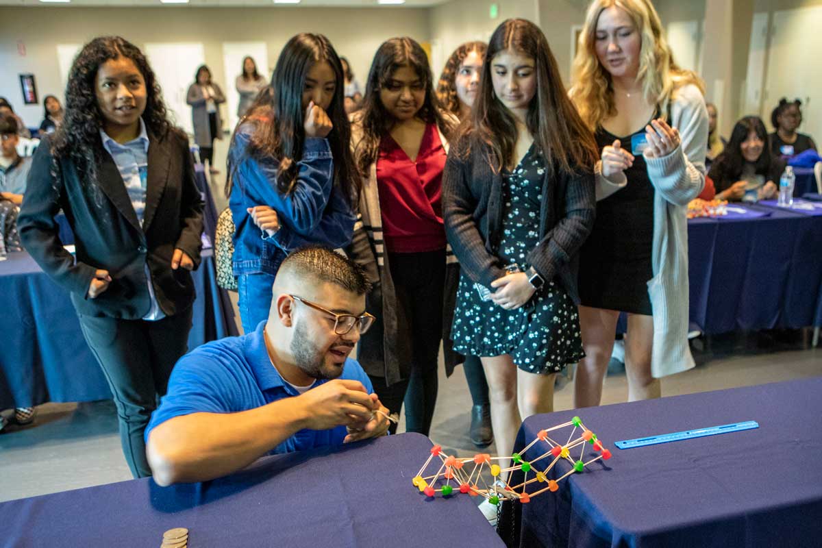 Students watch as a port engineer makes a "bridge" out of toothpicks.