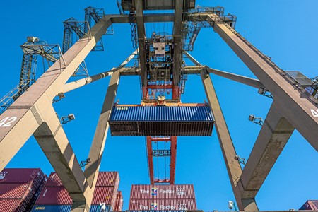 A container crane against a blue sky at the Port of Los Angeles