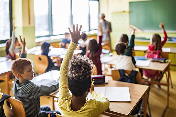Students with raised hands in a school classroom.