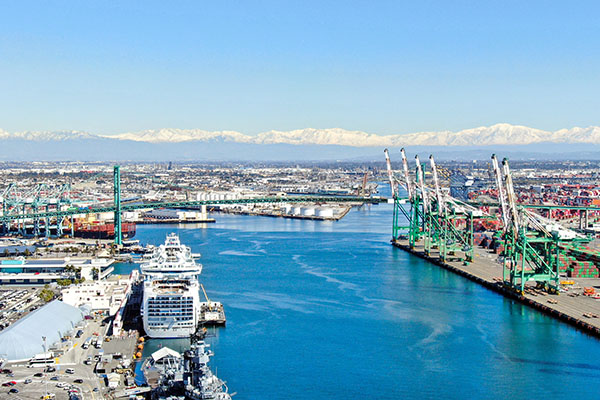 A quieter-than-usual Port of Los Angeles Main Channel against snow-covered mountains.