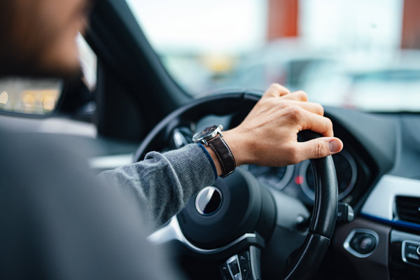 Out-of-focus driver behind the steering wheel of a car.